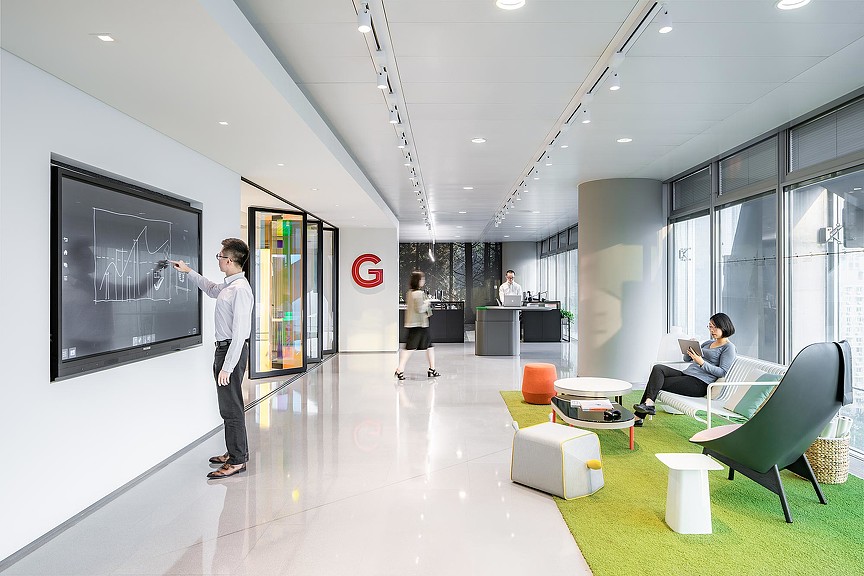 A man and a woman in a room with a large screen.